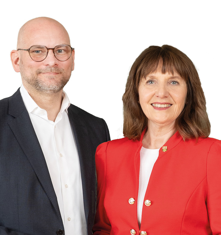 Drechsler_Praschak_Oberteil_2025-web Eine Frau mit roten Sakko und ein Herr links von ihr mit schwarzem Sakko