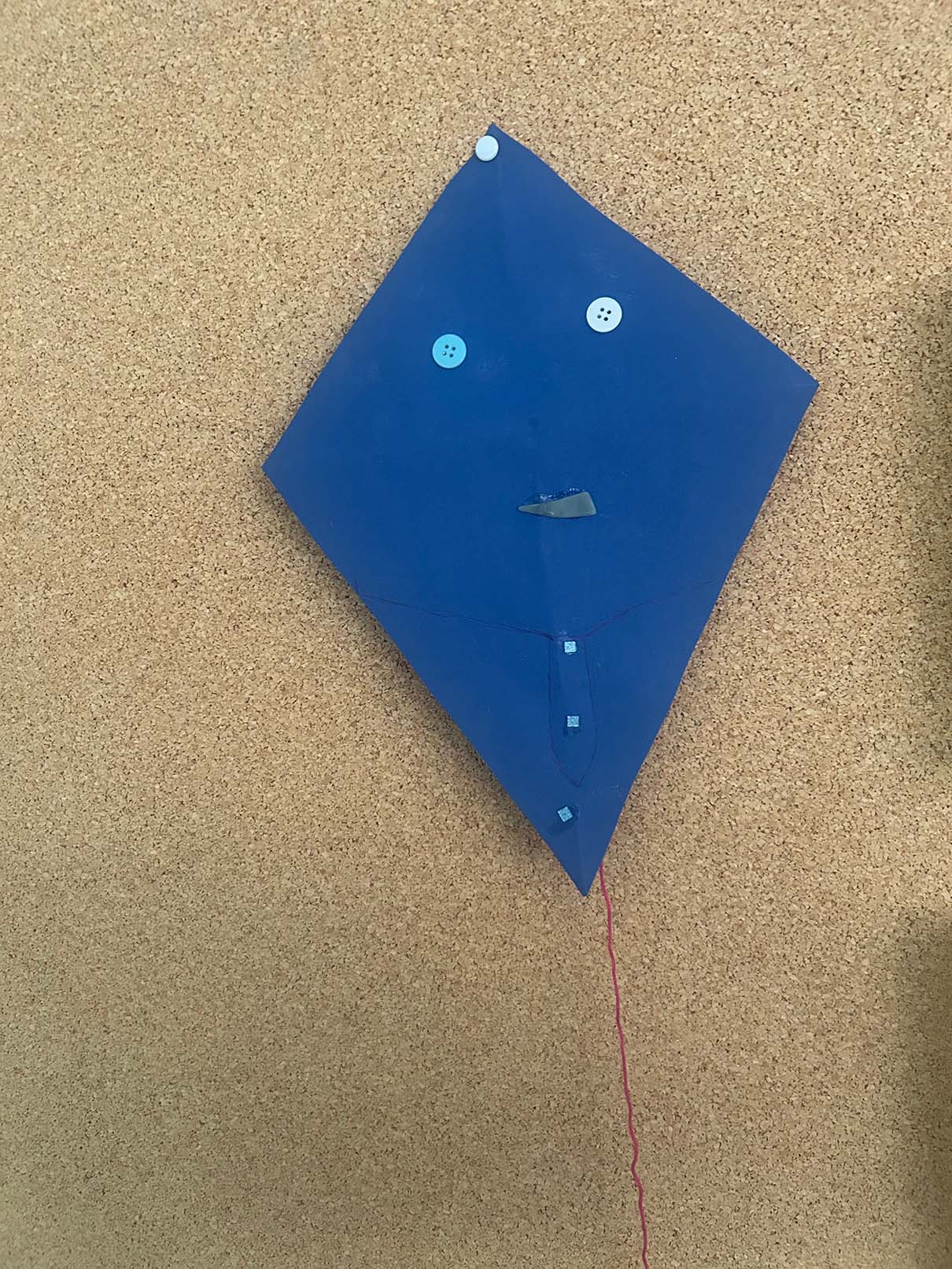 Ein blauer Selbstgemachter Flugdrache liegt auf dem Boden