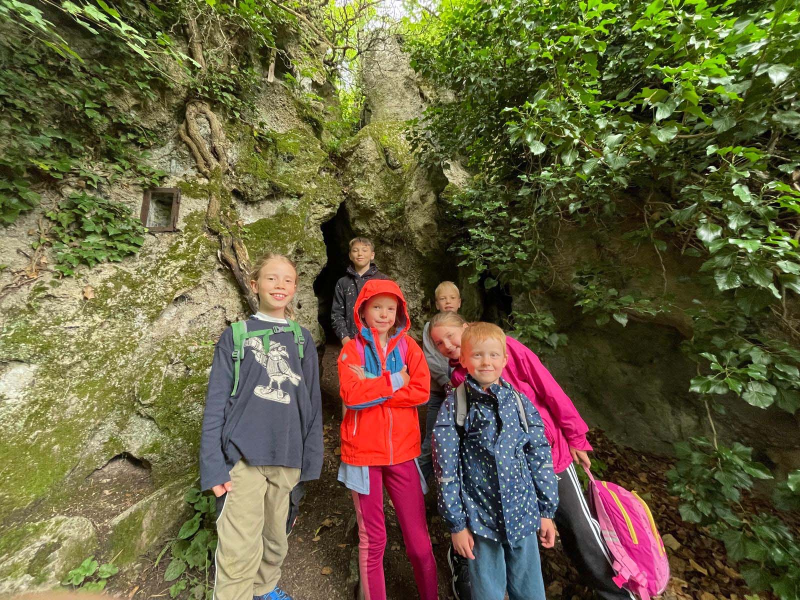 Mehrere Kinder stehen vor einer kleinen Höhle.