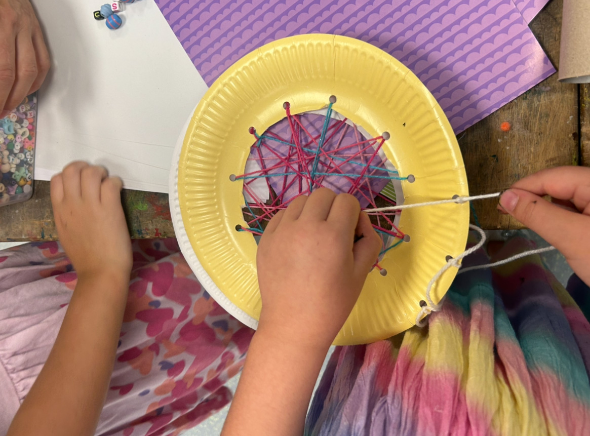 Kinder basteln einen eigenen Traumfänger aus einem Pappteller und Wolle