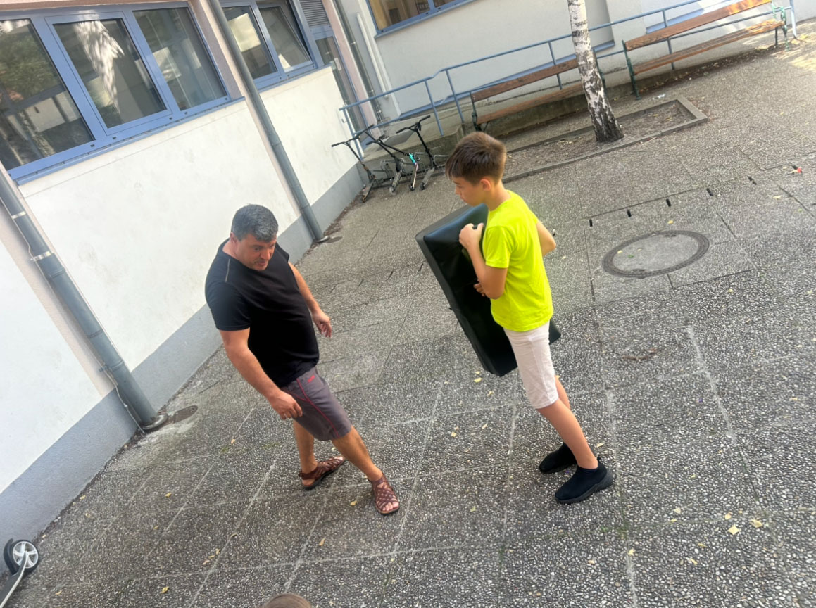 Ein erwachsener steht vor einem Kind mit einem Boxkissen