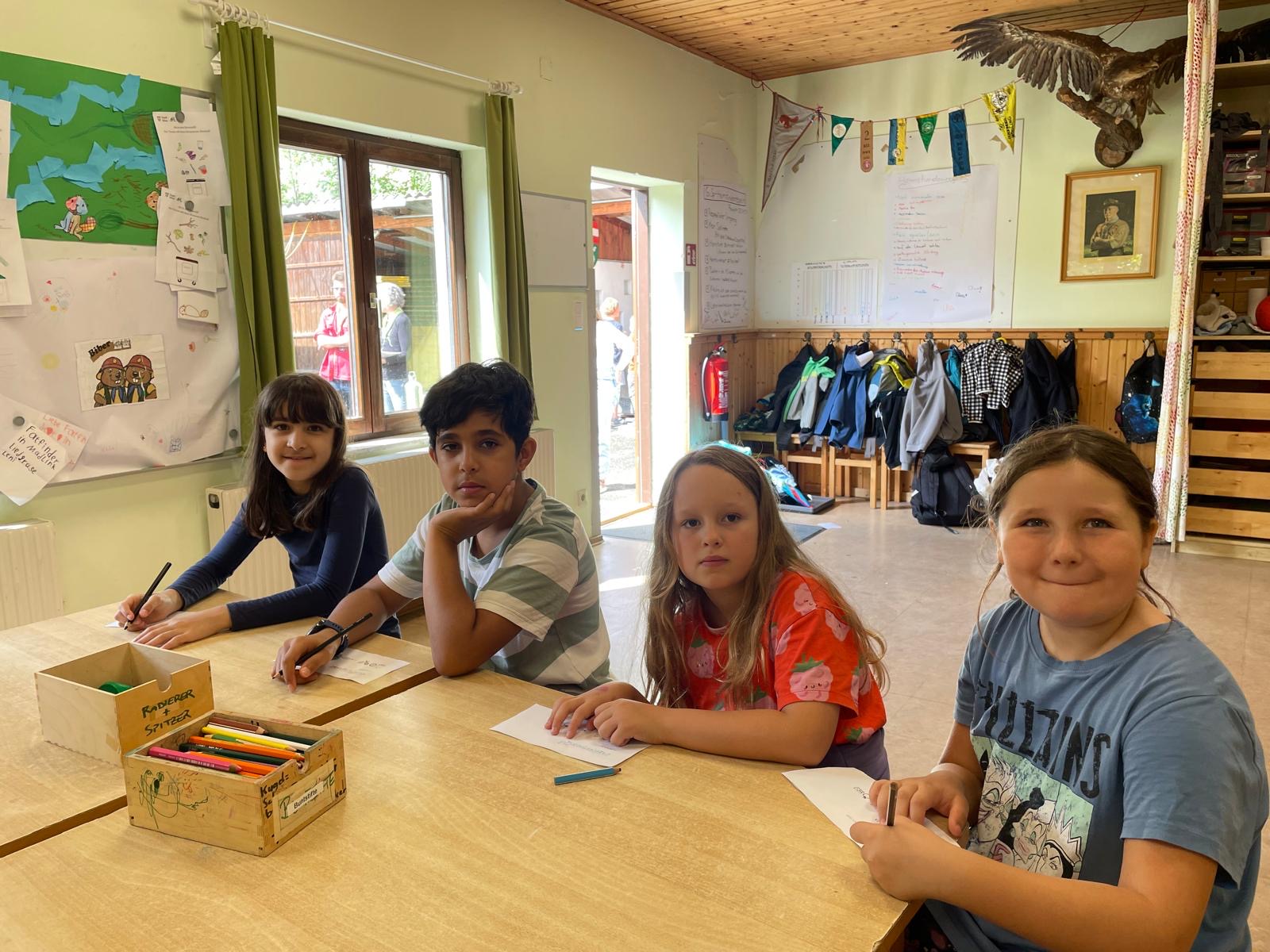 Kinder sitzen an einem Tisch und malen etwas