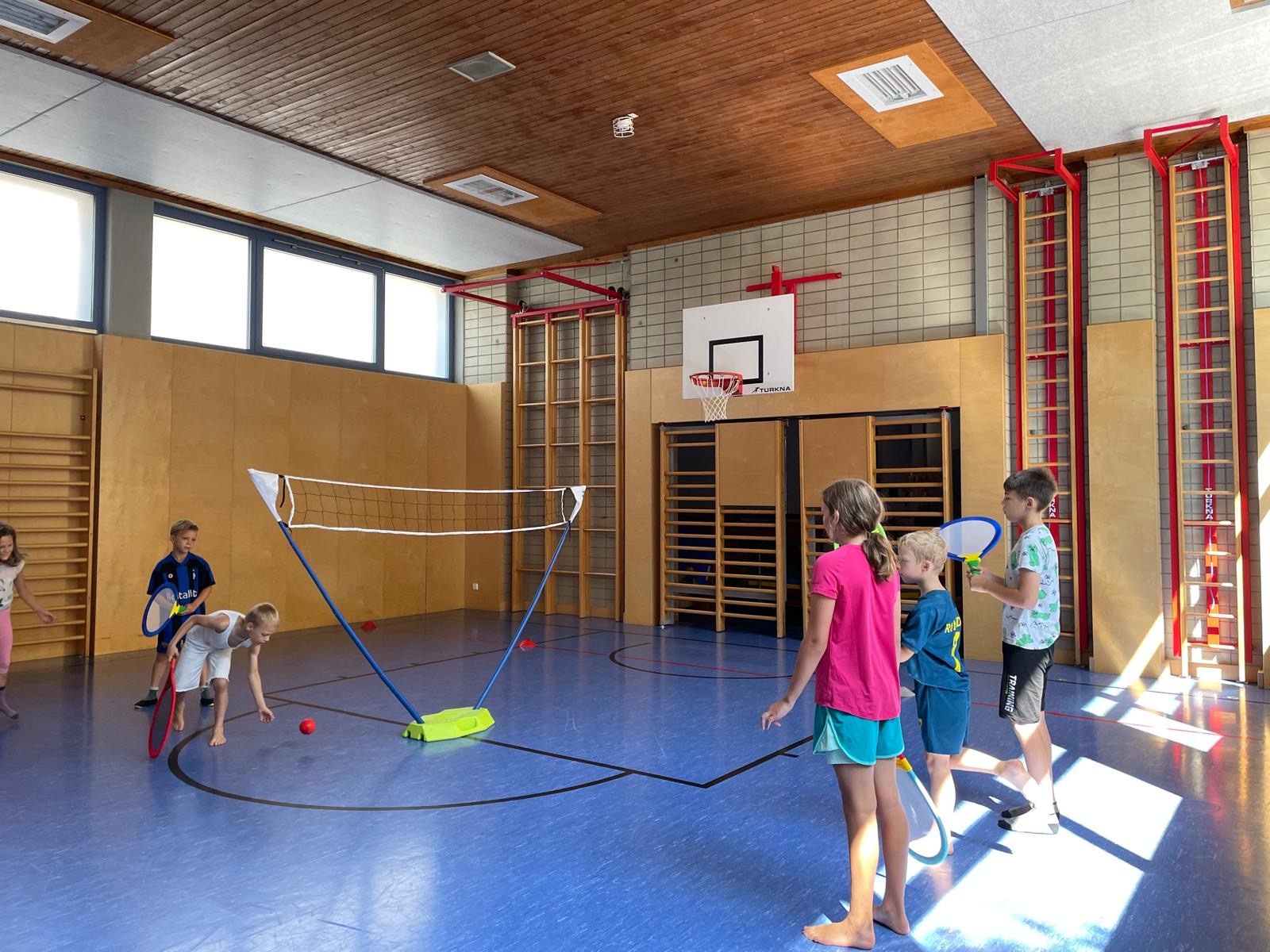 Eine Gruppe an Kindern spielt Streettennis