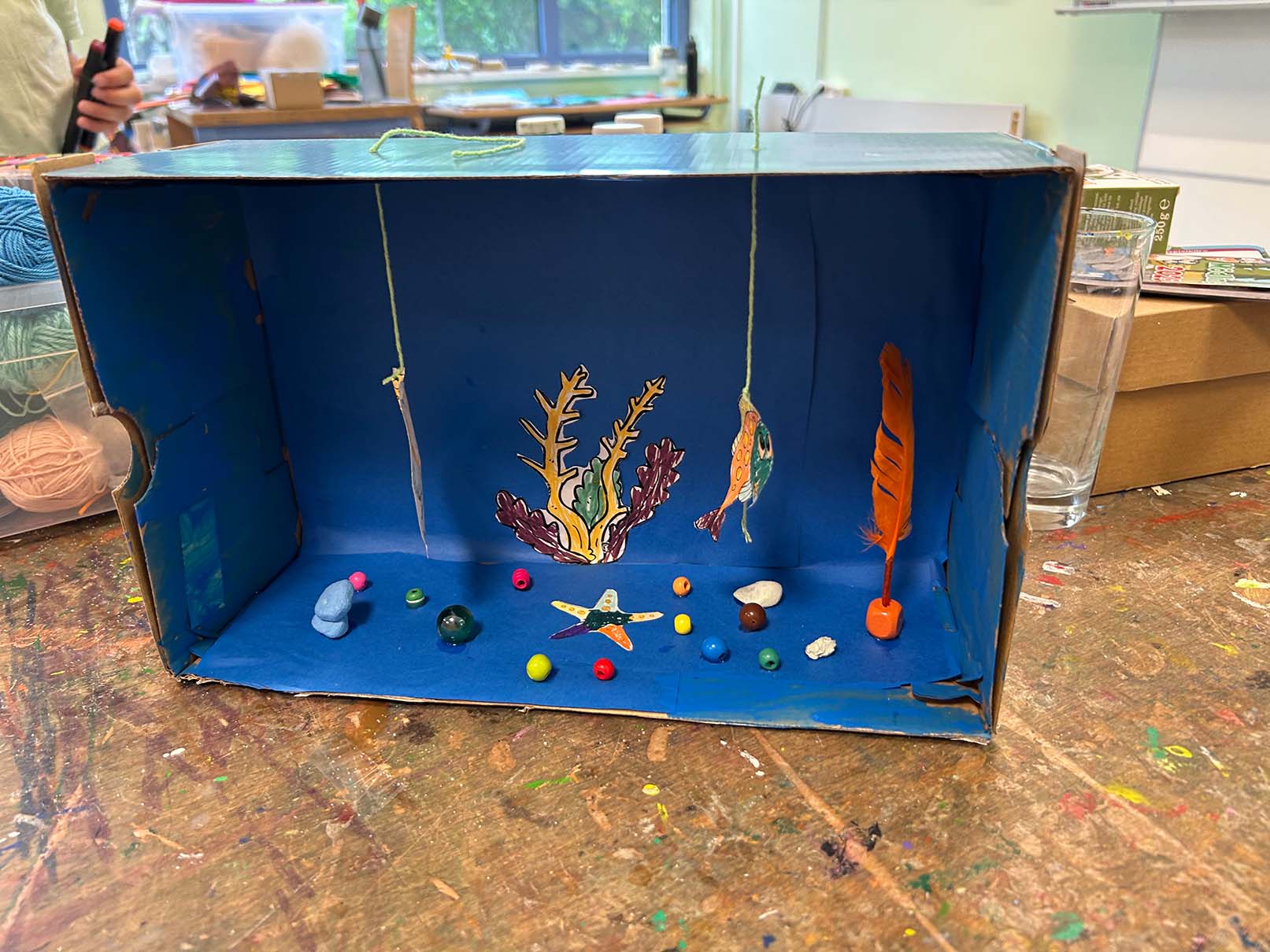 selbstgebasteltetes Aquarium aus Schukarton auf Basteltisch