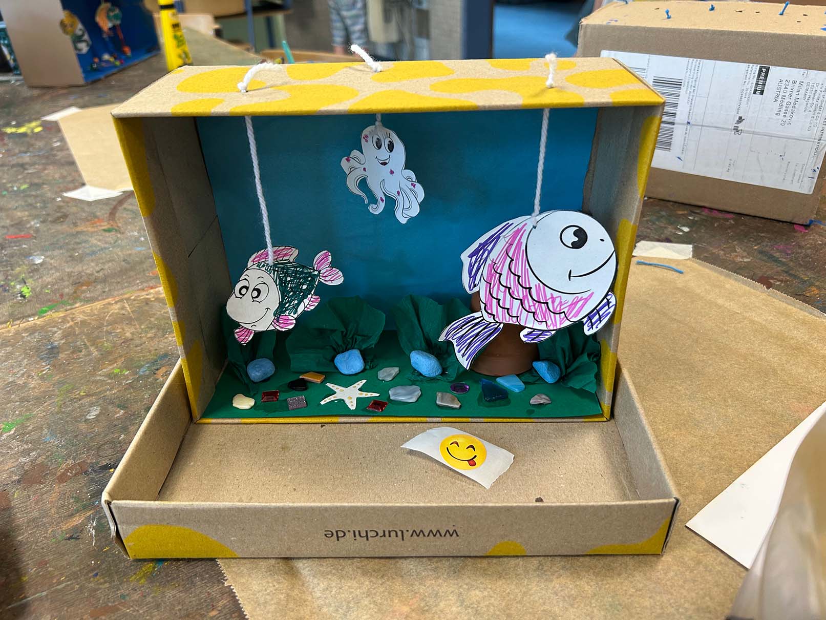 Selbstgemachtes Aquarium aus braunen Schukarton mit rosa Fischen