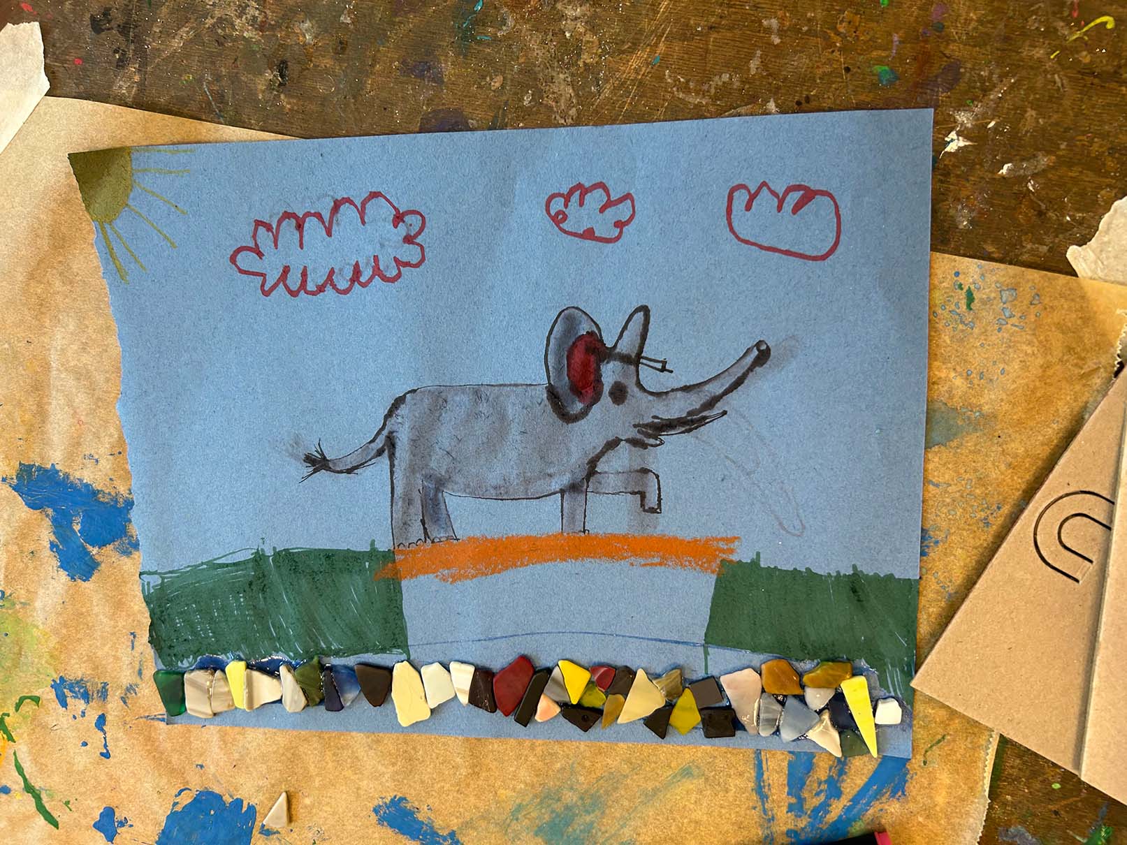 gezeichneter Elefant, welcher über eine Brücke geht mit Steinen auf dem Papier