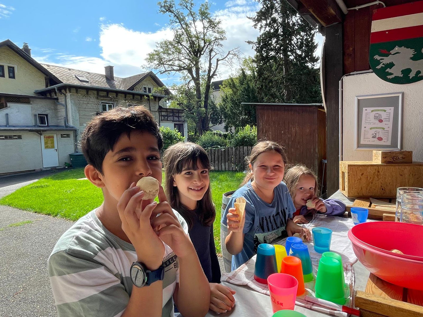 Ein paar Kinder sitzen an einem Tisch und formen Teig für Steckerlbrot