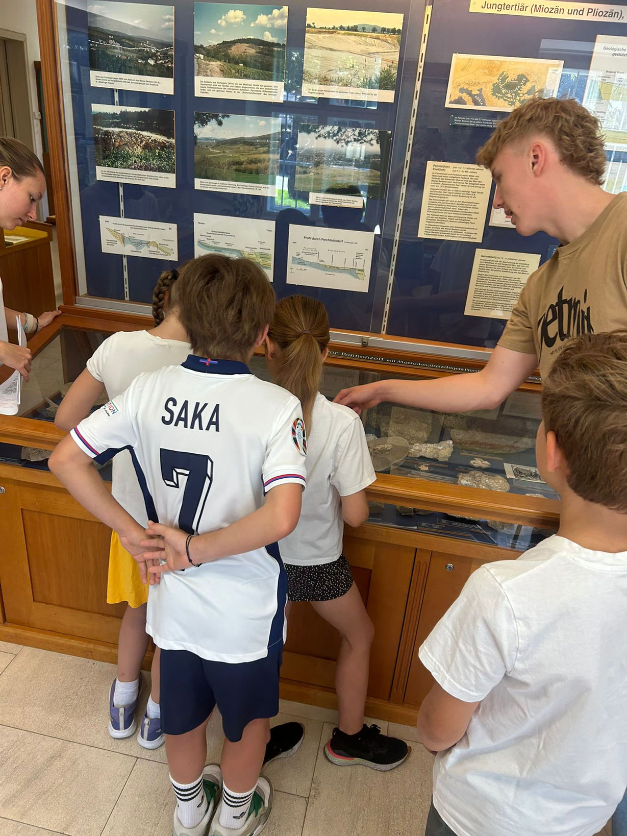 Einer Gruppe an Kindern wird etwas in einem Schaukasten gezeigt