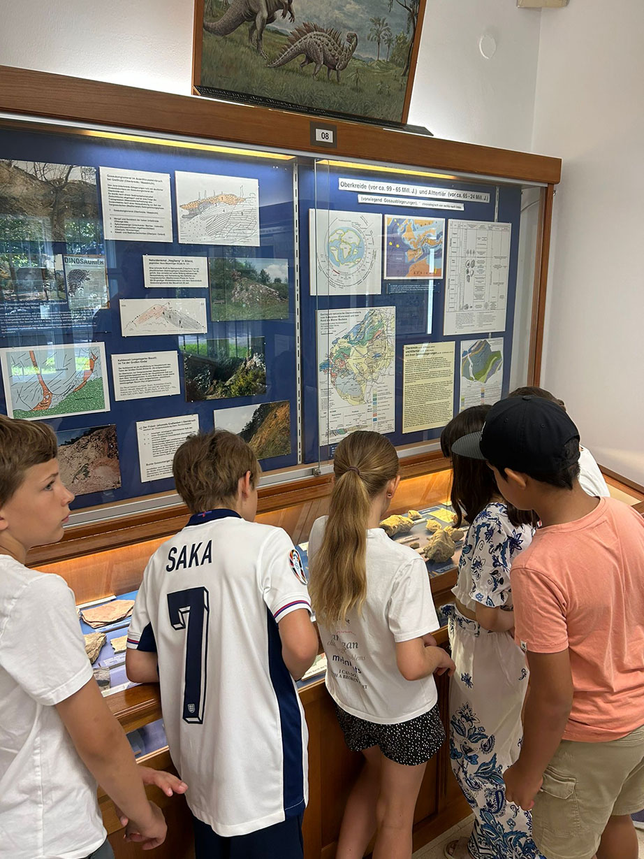 Eine Gruppe an Kindern, schaut sich etwas in einem Schaukasten an