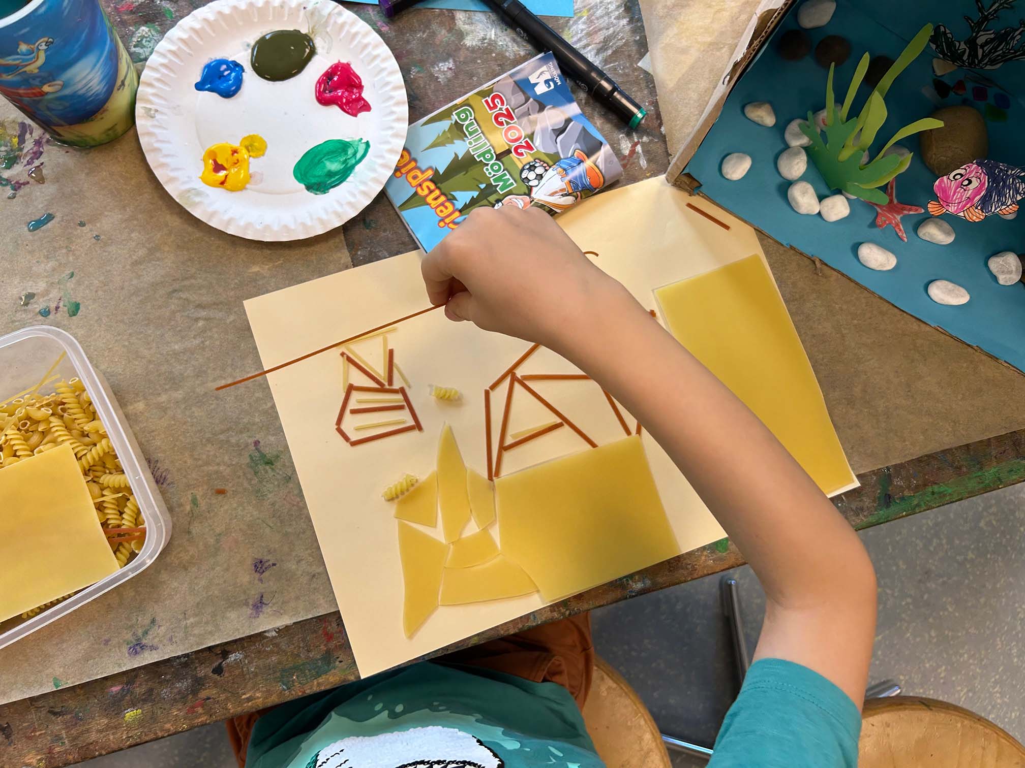 ein Kind macht ein Bild aus unterschiedlichen Nudeln